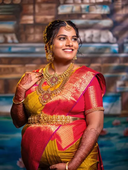 A radiant solo portrait capturing the expectant mother's joyful glow. The focus here is on her expression and the stunning details of her attire, including the temple jewelry and silk saree, essential for traditional maternity photography.