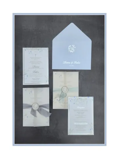 This invitation suite uses a cool ice blue and silver palette for a sophisticated and wintery feel. The set includes multiple inserts tied with a ribbon and sealed with a custom wax emblem, creating a classic and polished presentation.