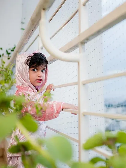 A curious glance from the birthday girl, framed by plants on her balcony. We look for creative angles to capture your child's personality.