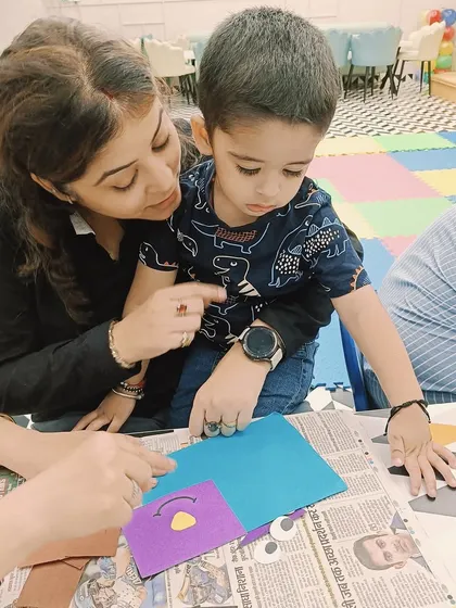 A mother points to a detail on a craft as her son looks on, a moment of shared learning and discovery.