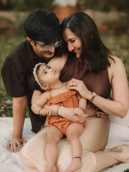 A candid moment of the family interacting on the blanket, with the parents looking lovingly at their daughter.