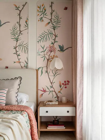 A detail of the daughter's room, showing the beautiful floral mural framed by simple moulding. The petal-like wall sconce adds a whimsical touch.