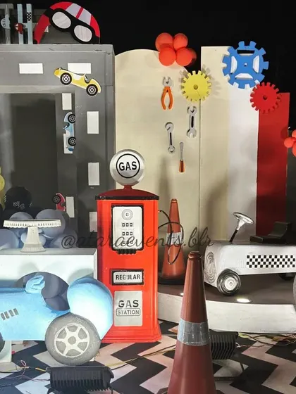 A full setup for a race car-themed second birthday. The decor includes a gas station, tires, tools, and car cutouts, creating a complete garage and racetrack environment.