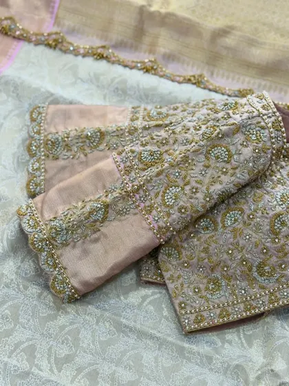 A peach blouse with all-over floral embroidery in gold and pearl.
