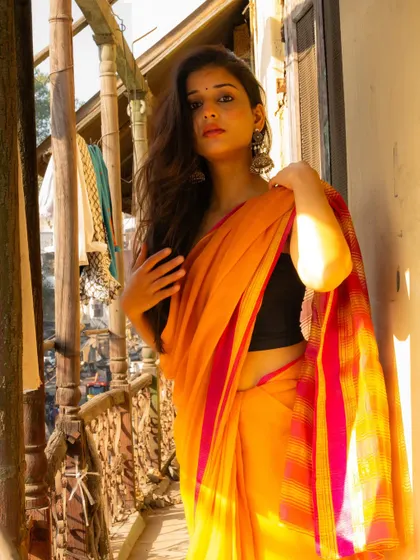 A confident portrait on the balcony, with the warm sunlight highlighting the colors of the saree and the model's features.