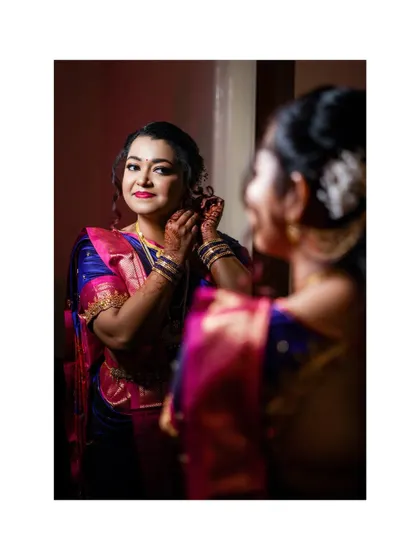 A candid getting-ready shot of the bride looking in the mirror before her engagement ceremony.