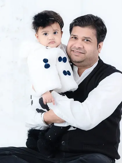 A father holds his daughter, who is dressed in a cute black and white outfit. A classic father-daughter portrait full of warmth.