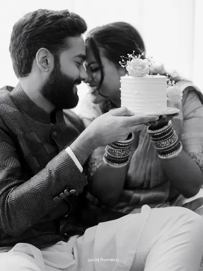 A tender black and white moment with a wedding cake, the focus on the couple's gentle interaction rather than the object.