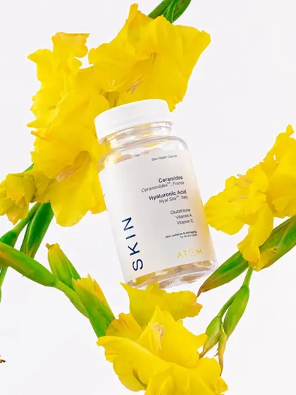 An artistic shot of Atom Health's supplement bottle surrounded by fresh yellow flowers. This composition uses natural elements to convey a sense of wellness and vitality.