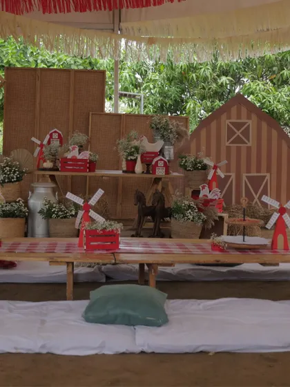 A low-seating picnic-style table for the kids at the farm party, decorated with a gingham runner, miniature windmills, and barn cutouts for a fun and immersive dining experience.