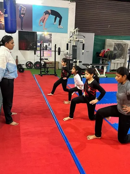 Our gymnastics program incorporates fitness training for all ages. Here, a coach is leading a group of older girls through lunges, focusing on building lower body strength and endurance.