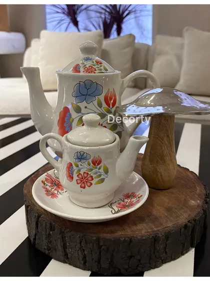 Themed table decor for a high tea party, featuring charming hand-painted teapots and a decorative mushroom on a rustic wood slice.