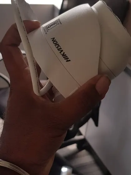 A close-up of a Hikvision dome camera in hand, showing its compact form factor.