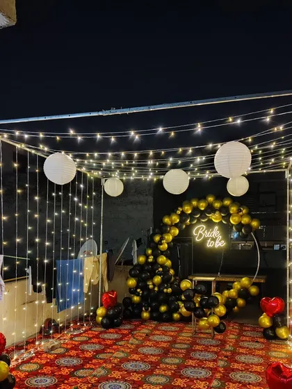 A custom 'Bride to be' neon sign adds a modern and trendy touch to this bachelorette party setup. It serves as a great photo prop within the fairy light canopy.