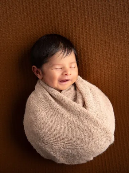 A simple "potato sack" swaddle is perfect for capturing those sleepy smiles. With all distractions removed, the focus is entirely on the baby's happy expression.