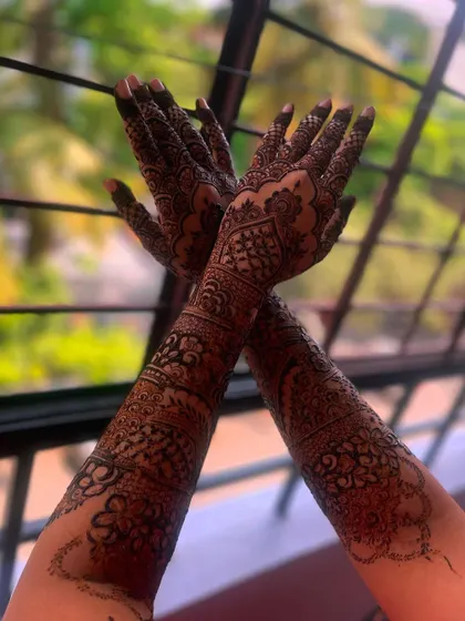 A crossed-hands pose showcasing the beautiful and intricate bridal henna design.