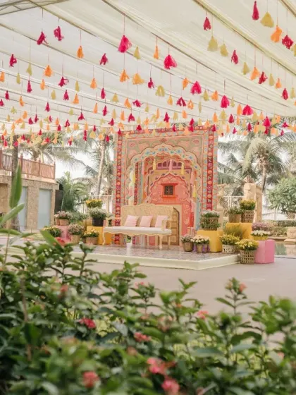 A wide view of the vibrant Haldi setup, with a canopy of colorful tassels and a beautifully designed stage area.
