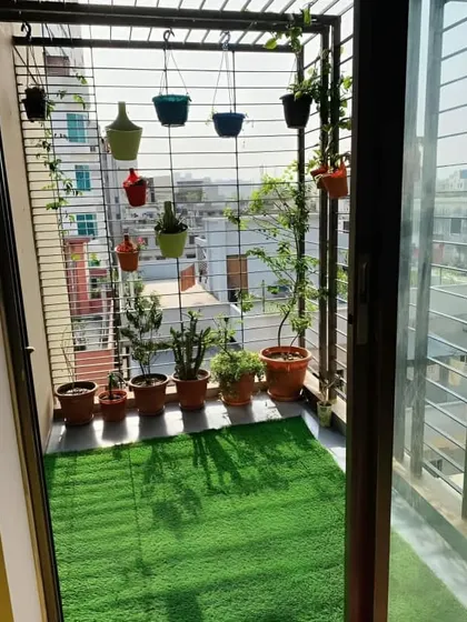 Even a narrow, grilled balcony can become a charming garden. This makeover uses low-maintenance artificial grass flooring, a row of potted plants, and colorful hanging pots to bring life and color to the space.