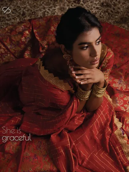 She wears the crown of poise and charm. In a statement red lehenga, she is an ethereal embrace of timeless grace.