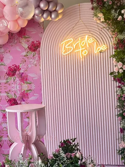 A close-up of this pink 'Bride to be' setup, highlighting the neon sign against a textured arch. The combination of balloons, a custom floral wallpaper, and fresh flowers created a rich, layered look.