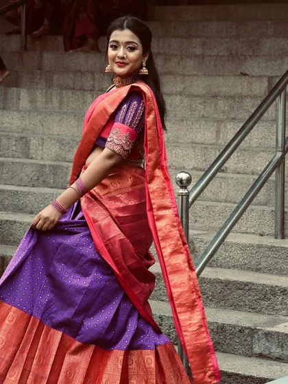 The full view of the purple and pink half saree, showing the flow of the skirt and the elegance of the traditional drape.