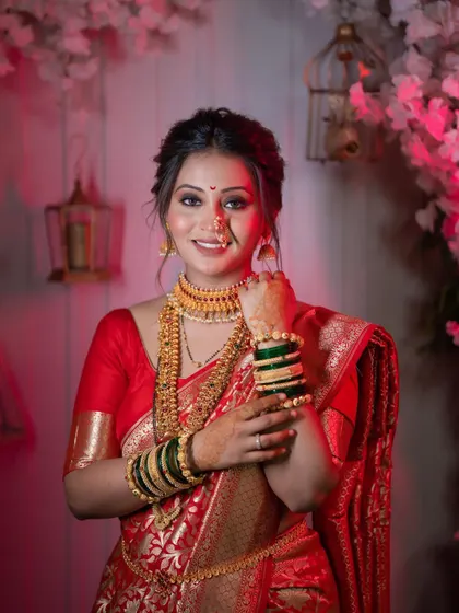 A stunning bridal portrait against a backdrop of pink flowers and birdcages, highlighting the bride's intricate gold jewelry.