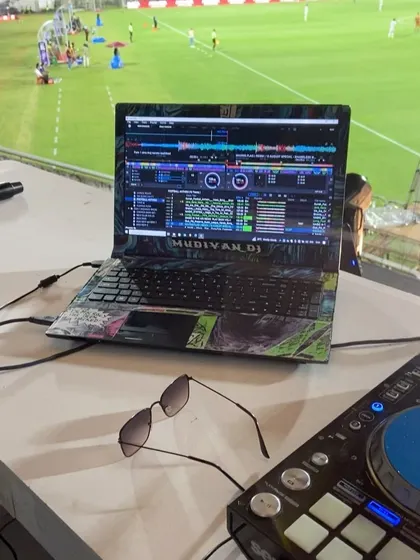 The view from my DJ booth at a Kerala Super League football match. My custom-skinned laptop is ready for action.