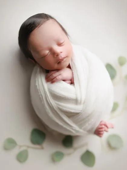 A touch of green. This minimal setup with a simple white wrap and a few eucalyptus leaves creates a fresh, natural, and modern portrait.