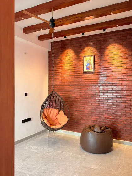 A cozy relaxation corner featuring an exposed brick wall and a hanging swing chair. This space is designed for unwinding and adds a touch of rustic charm to the modern home.