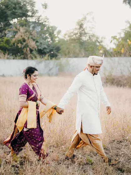 A simple and sweet shot of the couple walking hand-in-hand through a field.