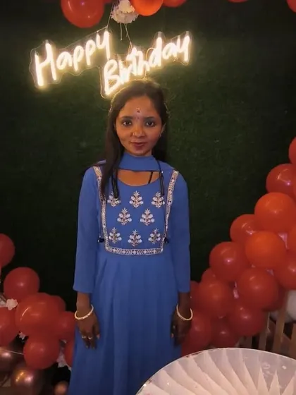 A happy customer posing in front of our green wall birthday setup. The combination of red balloons and a 'Happy Birthday' neon sign looks great in photos.