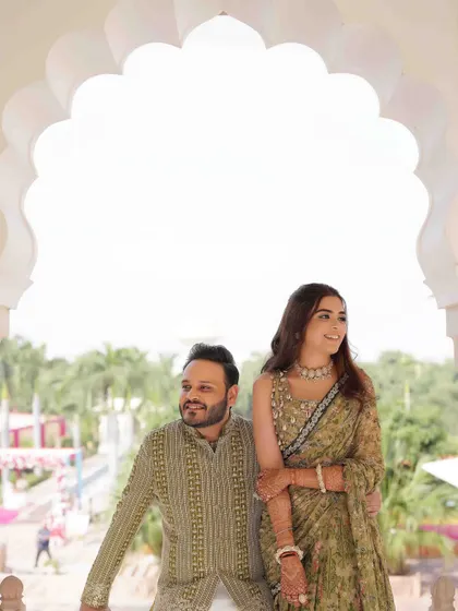 A beautifully composed portrait of the couple framed by a white archway, the lush greenery in the background adding to the serene atmosphere.