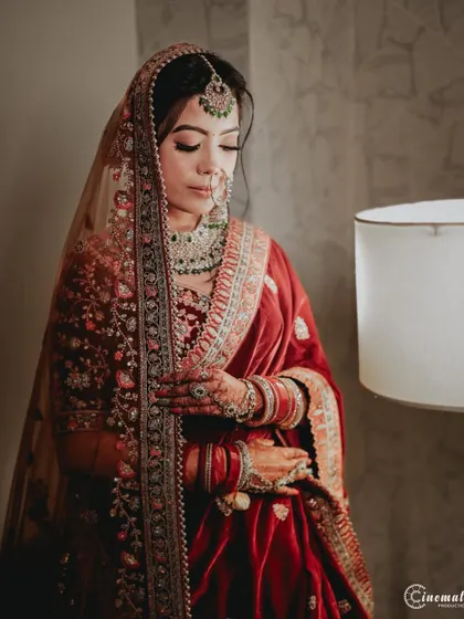 A classic bridal portrait, capturing the elegance of her velvet lehenga and the quiet moments before the ceremony.