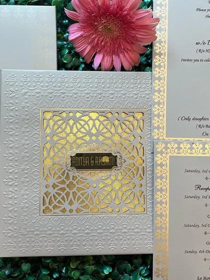 Another angle of the white and gold 'jaali' invitation, highlighting the texture of the card and the shine of the gold foil.