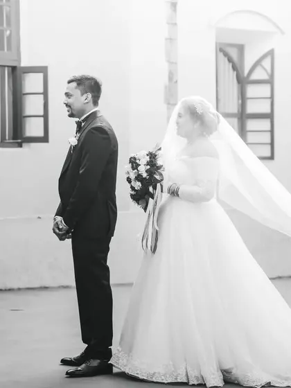 The beginning of a "first look" sequence, captured in black and white. The bride approaches the groom, her long veil flowing behind her.