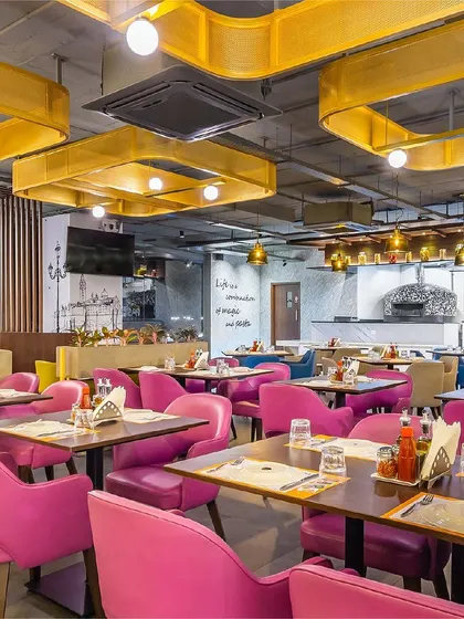 A vibrant dining section at Pasta Street, where bold pink chairs create a striking contrast against the custom yellow ceiling fixtures. This area was designed to be energetic and memorable, reflecting the lively spirit of the Italian street food concept.