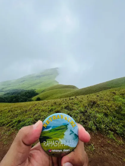The Netravathi badge held against the iconic view of the peak's ridge. This is the shot everyone wants to get.