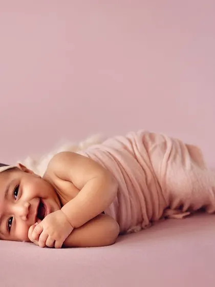 A happy baby girl lying on her side during her 4-month milestone session. Her bright smile and cheerful expression are simply infectious.