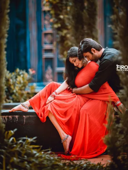 A romantic and intimate embrace in a garden. The soft, natural light and the framing of the leaves create a very beautiful and private feel.