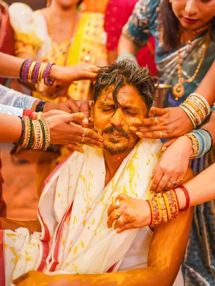 A touching moment as a family member applies Haldi to the groom. These candid shots capture the love and blessings that surround the couple.
