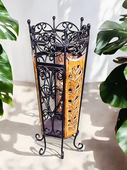 A functional and decorative umbrella stand crafted from wood and metal. The ornate black metal scrollwork contrasts beautifully with the carved wooden panels, making it a stylish addition to your entryway.