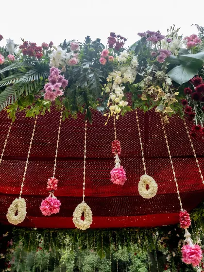 A close-up of a floral arrangement with red and pink flowers against a textured red backdrop.