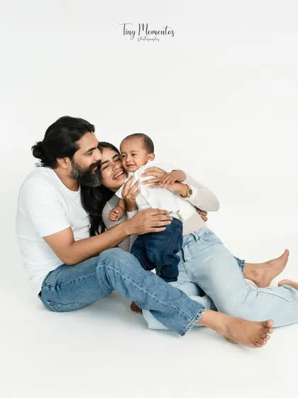 A joyful family cuddle on the floor. The relaxed, casual posing in matching white shirts and jeans creates a feeling of comfort and happiness, a perfect snapshot of family bliss.