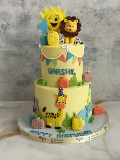 Roaring into sweetness with this sunny jungle-themed cake for Varshil's first birthday. A happy sun topper shines down on a lion, giraffe, and other cute animals.