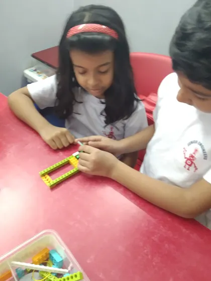 Two students work together to assemble the chassis of a robot, learning about structural integrity and teamwork.