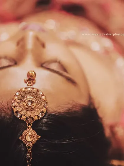 A creative top-down shot focusing on the bride's ornate maang tikka, a beautiful detail of her bridal jewelry.