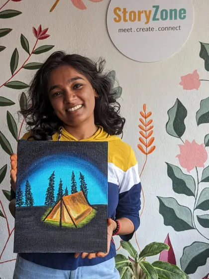A participant with her finished camping-themed canvas painting, set against our beautiful studio wall.