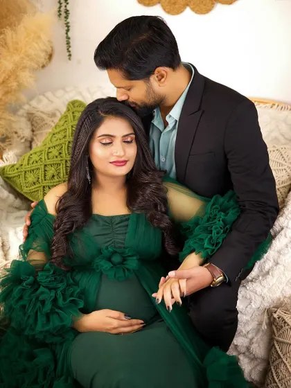 An intimate moment during a boho-themed maternity shoot. The husband's gentle kiss and the soft lighting highlight the couple's love and excitement.