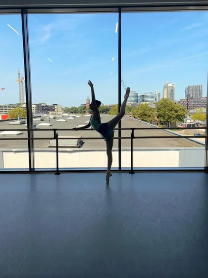 A beautiful silhouette of Jazmine Bhanushali at the Dutch National Ballet Academy's Summer School, with the city of Amsterdam in the background.