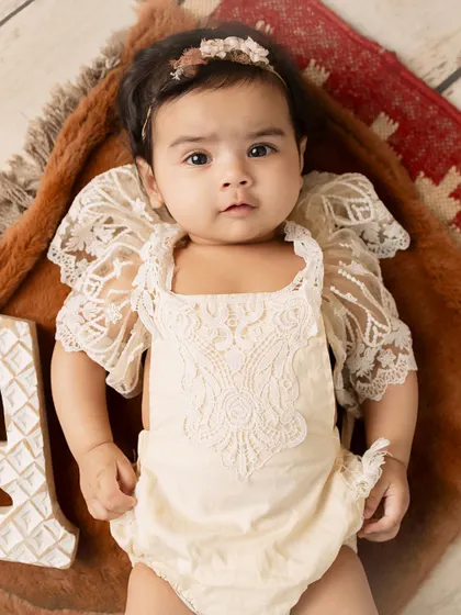 A classic portrait. This baby's direct gaze and the delicate details of her outfit make for a timeless and beautiful image.